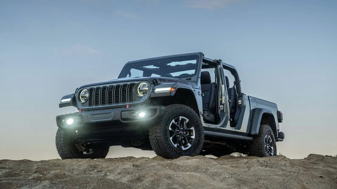 Gray Jeep Gladiator Rubicon off-roading at night with headlights on.