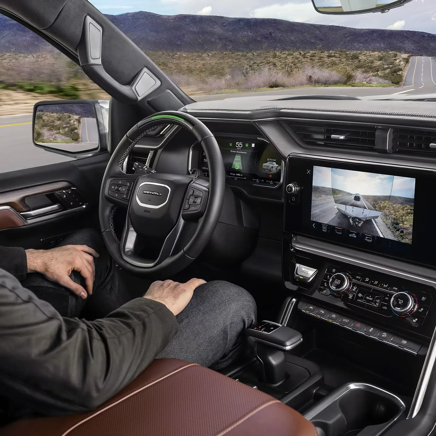 Conducteur au volant d'un GMC Sierra 1500, avec l'&eacute;cran affichant les technologies de remorquage.