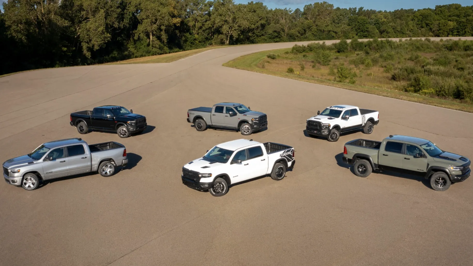 Several RAM 1500 trucks in different trims parked together on a paved area surrounded by greenery.