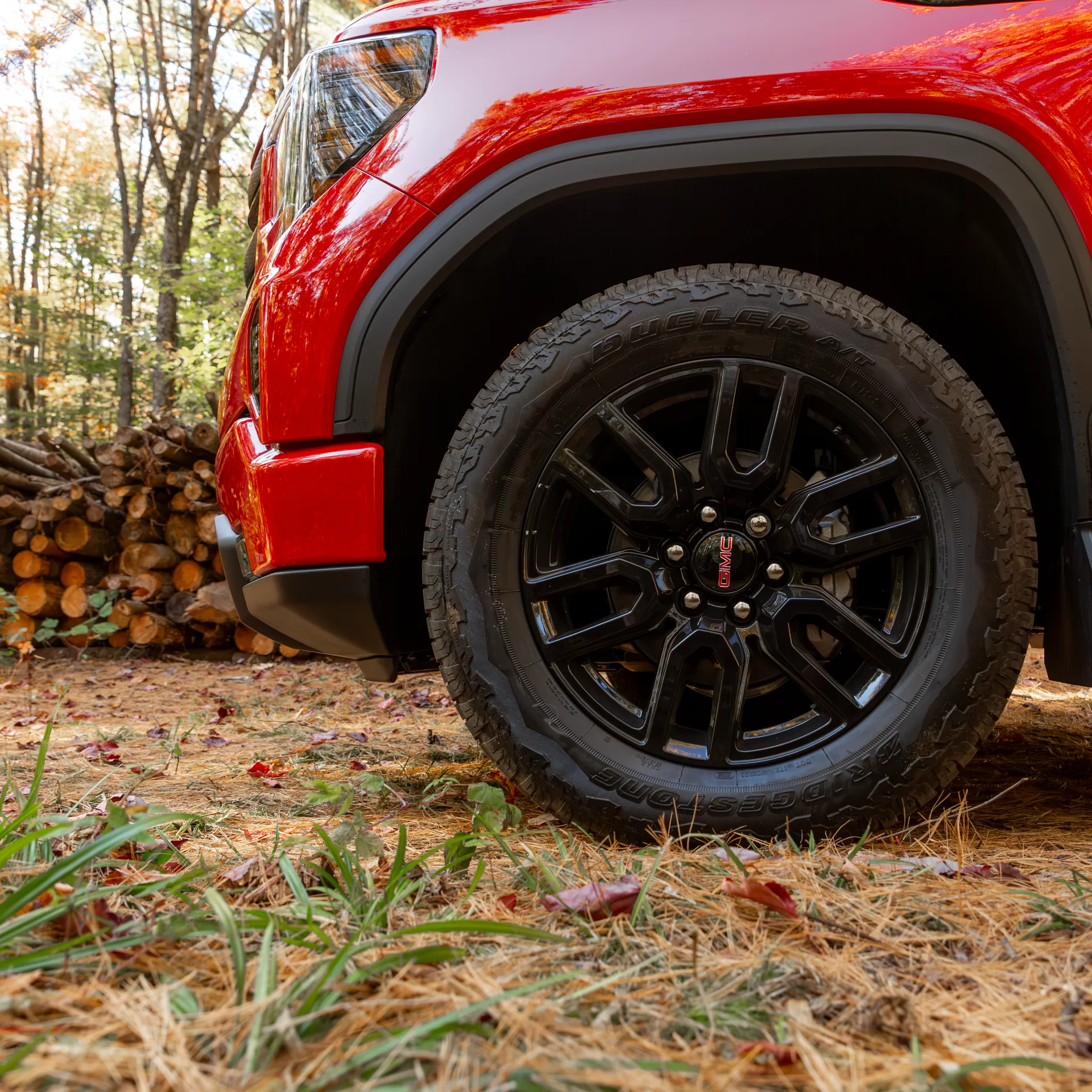 Gros plan sur l'aile avant rouge et la roue noire du GMC Sierra 1500 2027