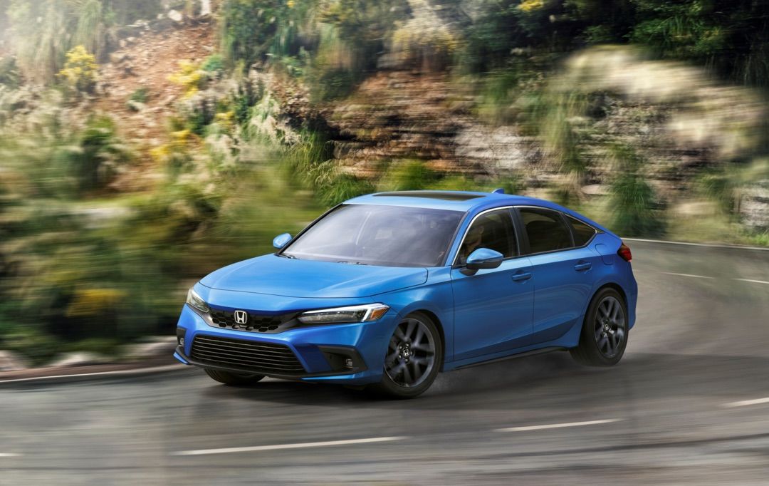 La Honda Civic Hatchback 2022 bleue effectuant un virage brusque dans un tournant sur la route