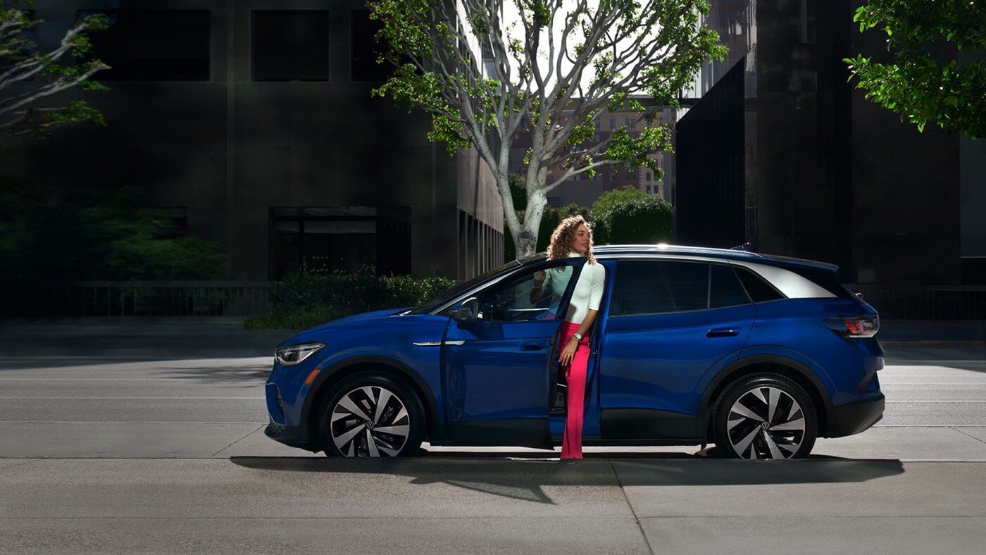 Vue latérale d'un VUS électrique Volkswagen ID.4 2022 avec une femme sortant du véhicule