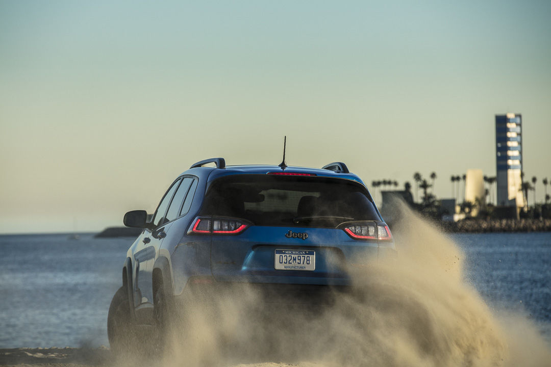 Rear view of the 2022 Jeep Cherokee Trailhawk driving on sand.