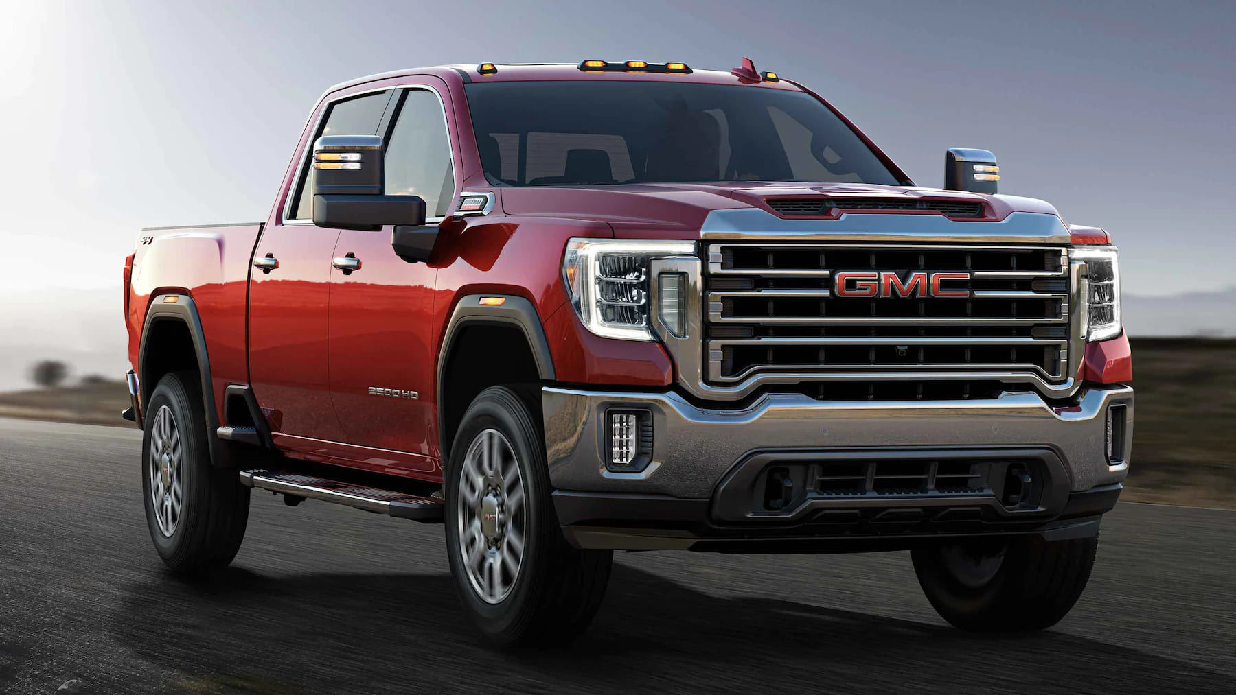 Front 3/4 view of a GMC Sierra driving on a road.