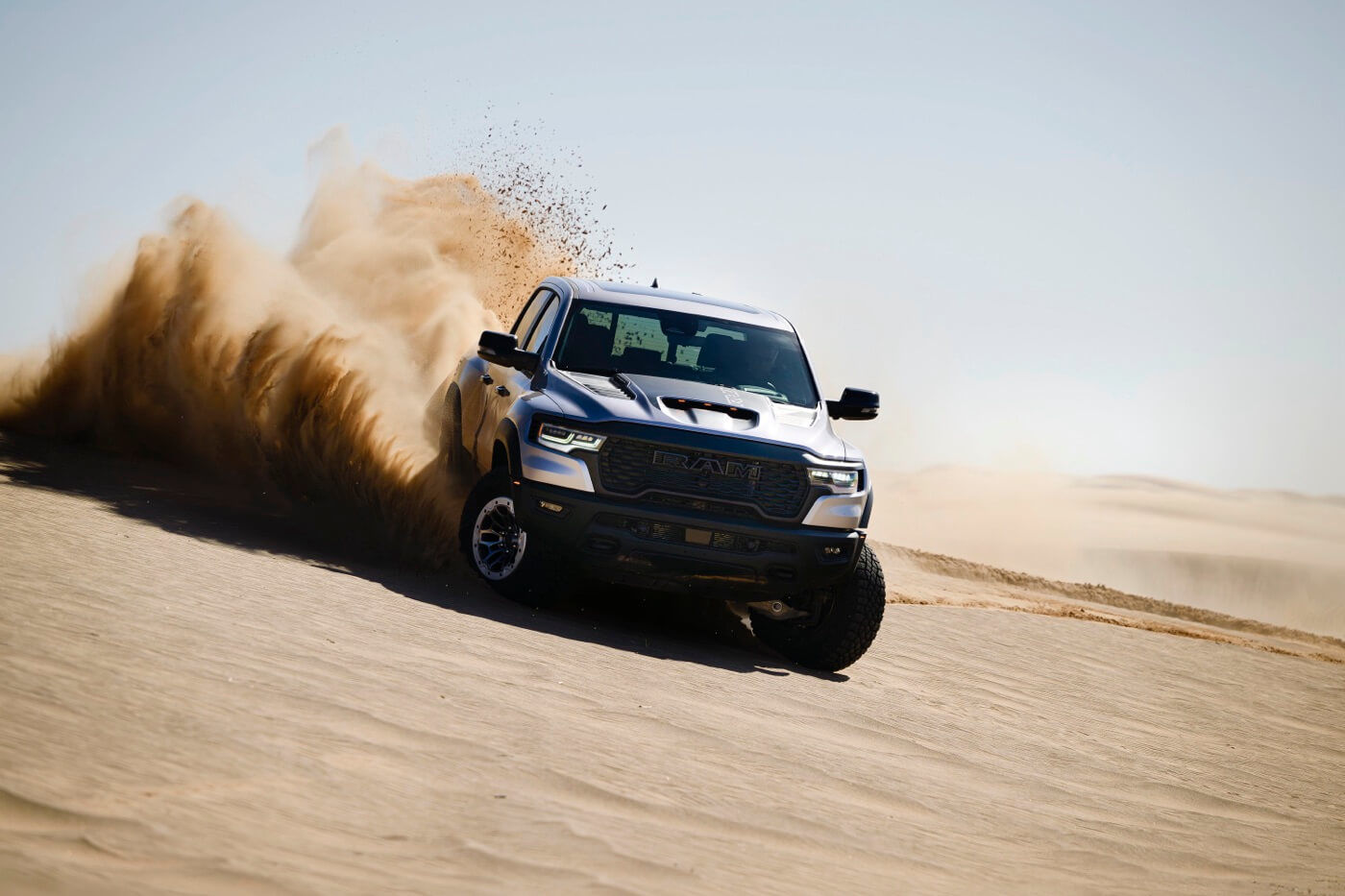 The 2025 RAM 1500 driving in the sand.