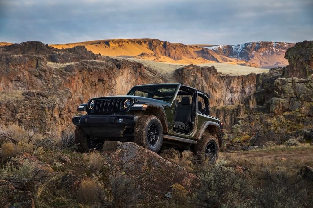 The 2024 Jeep Wrangler parked on a rock in the mountains.