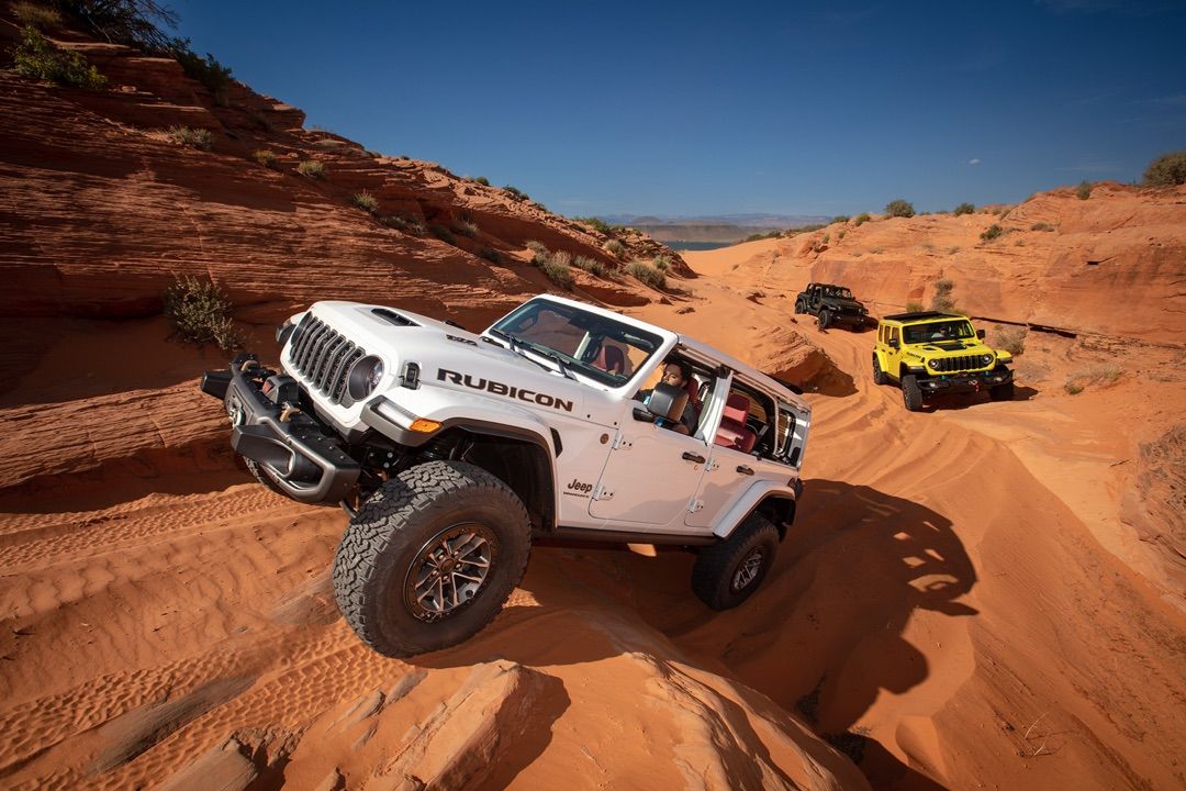 Three 2024 Jeep Wrangler SUVs following each other in a desert.