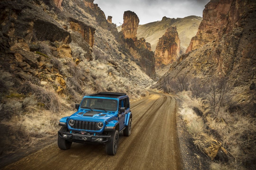 A Jeep Wrangler 4xe driving on a dirt road.