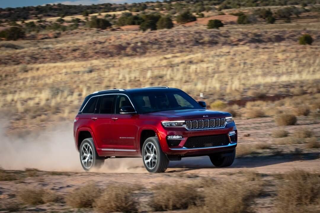 Vue 3/4 avant du Jeep Grand Cherokee 2024 rouge roulant sur un chemin de terre.