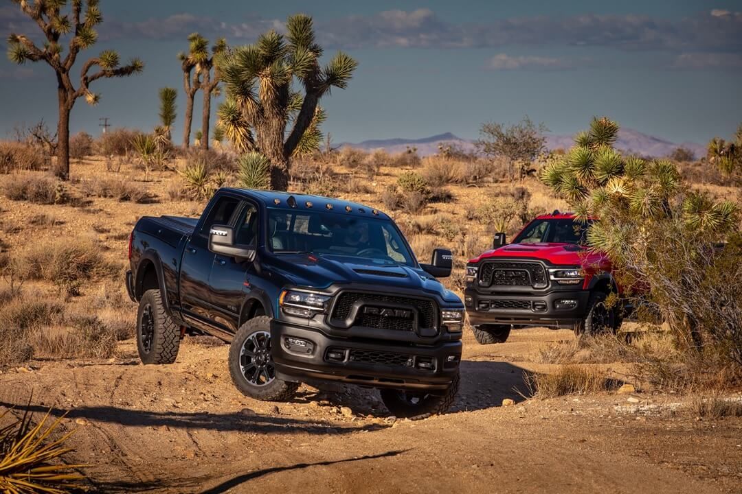 Two RAM 2500 trucks in a desert.