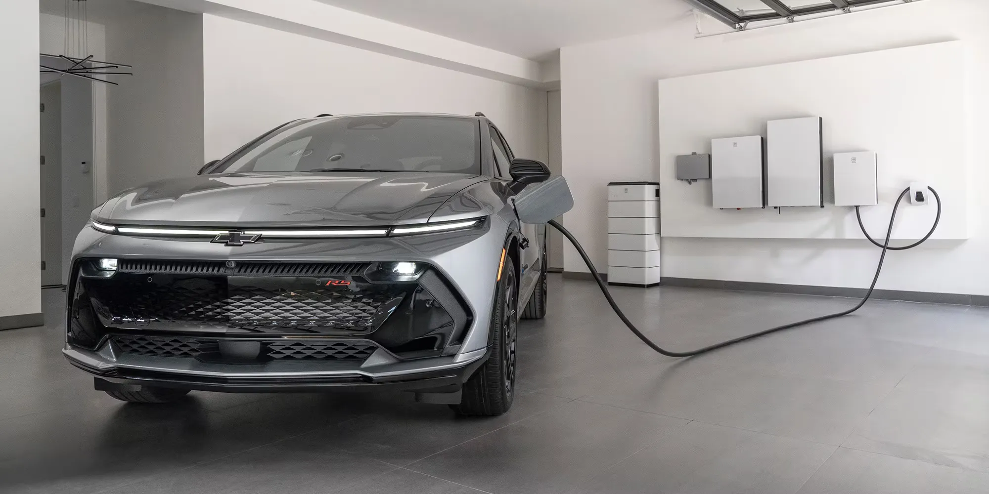 Chevrolet Equinox EV RS branch&eacute; &agrave; une borne de recharge r&eacute;sidentielle dans un garage