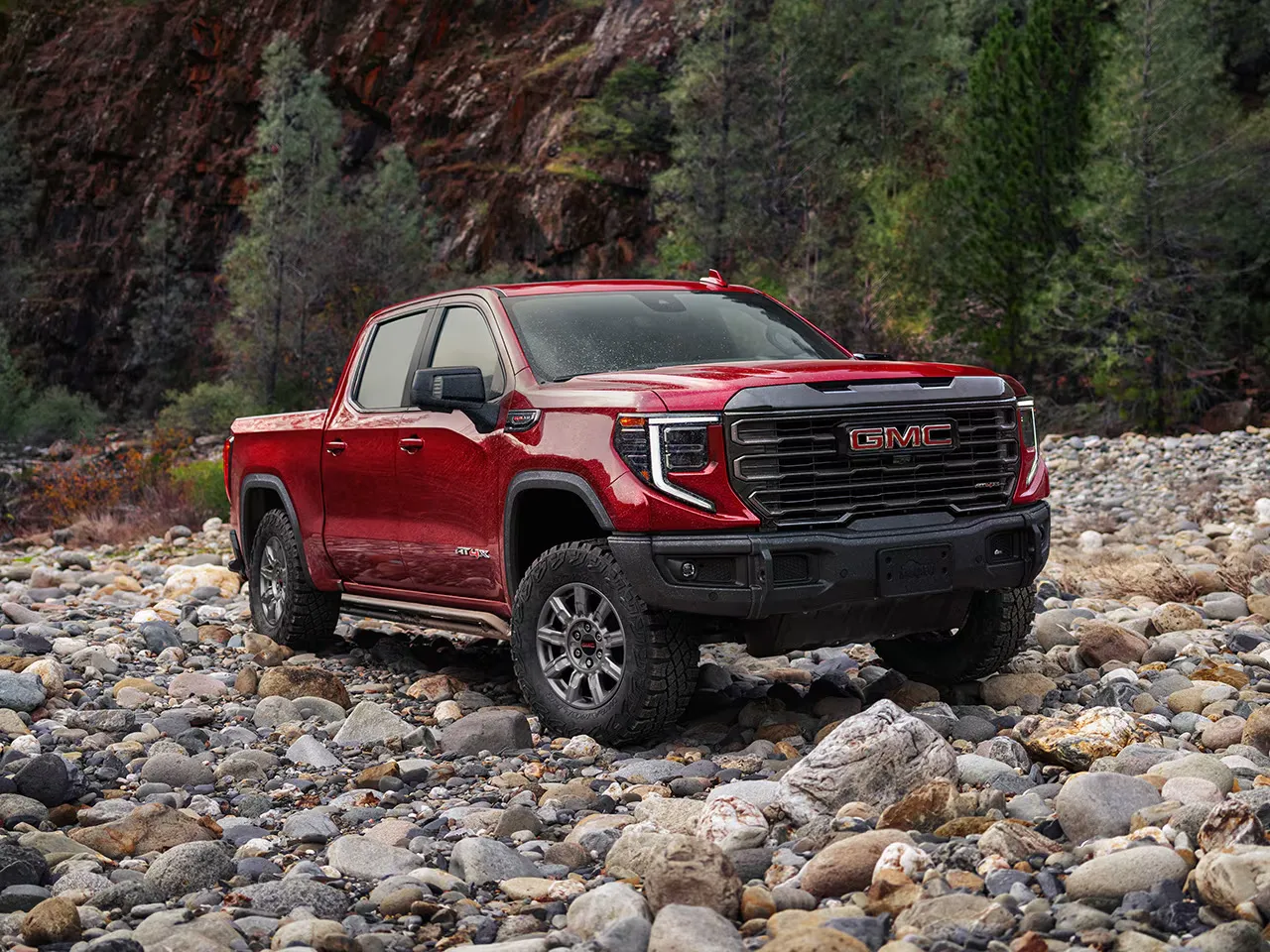 GMC Sierra 1500 AT4 2026 rouge sur terrain rocailleux, version tout-terrain.