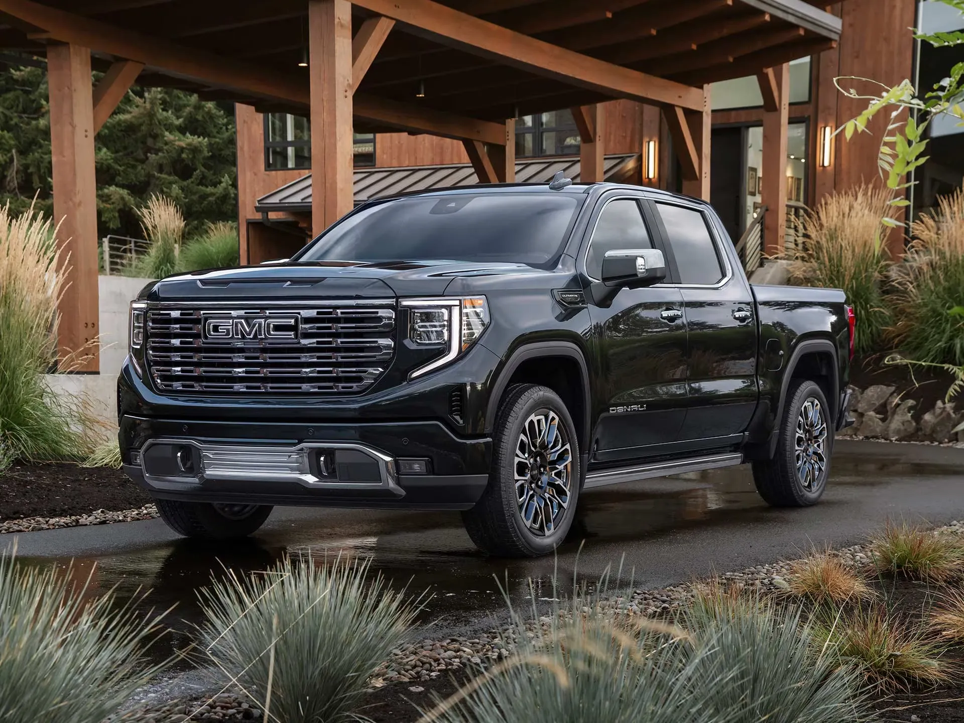 GMC Sierra 1500 Denali Ultimate 2026 noir stationn&eacute; devant un chalet moderne.