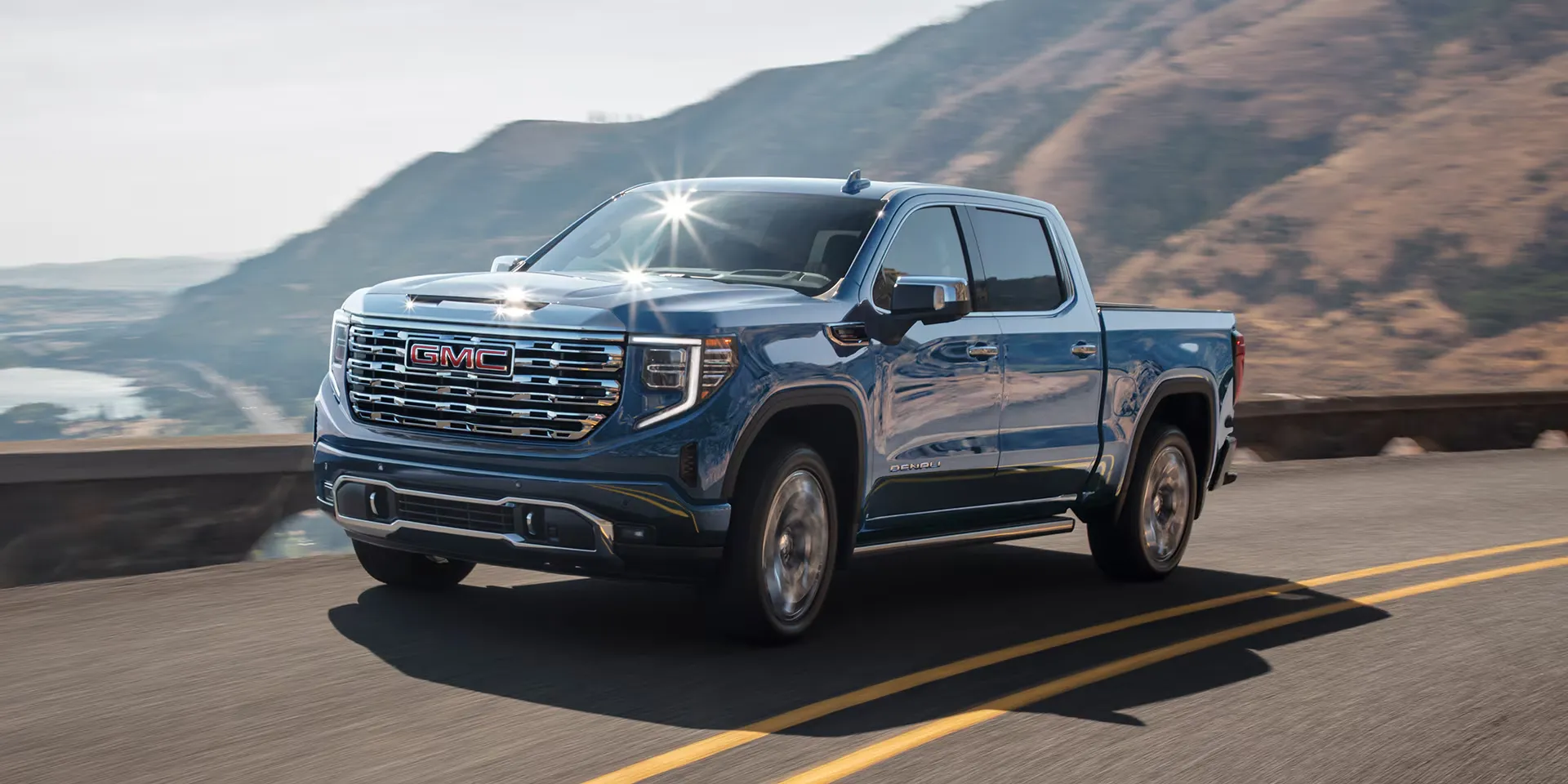 GMC Sierra 1500 Denali 2026 bleu sur route panoramique, version ax&eacute;e confort.