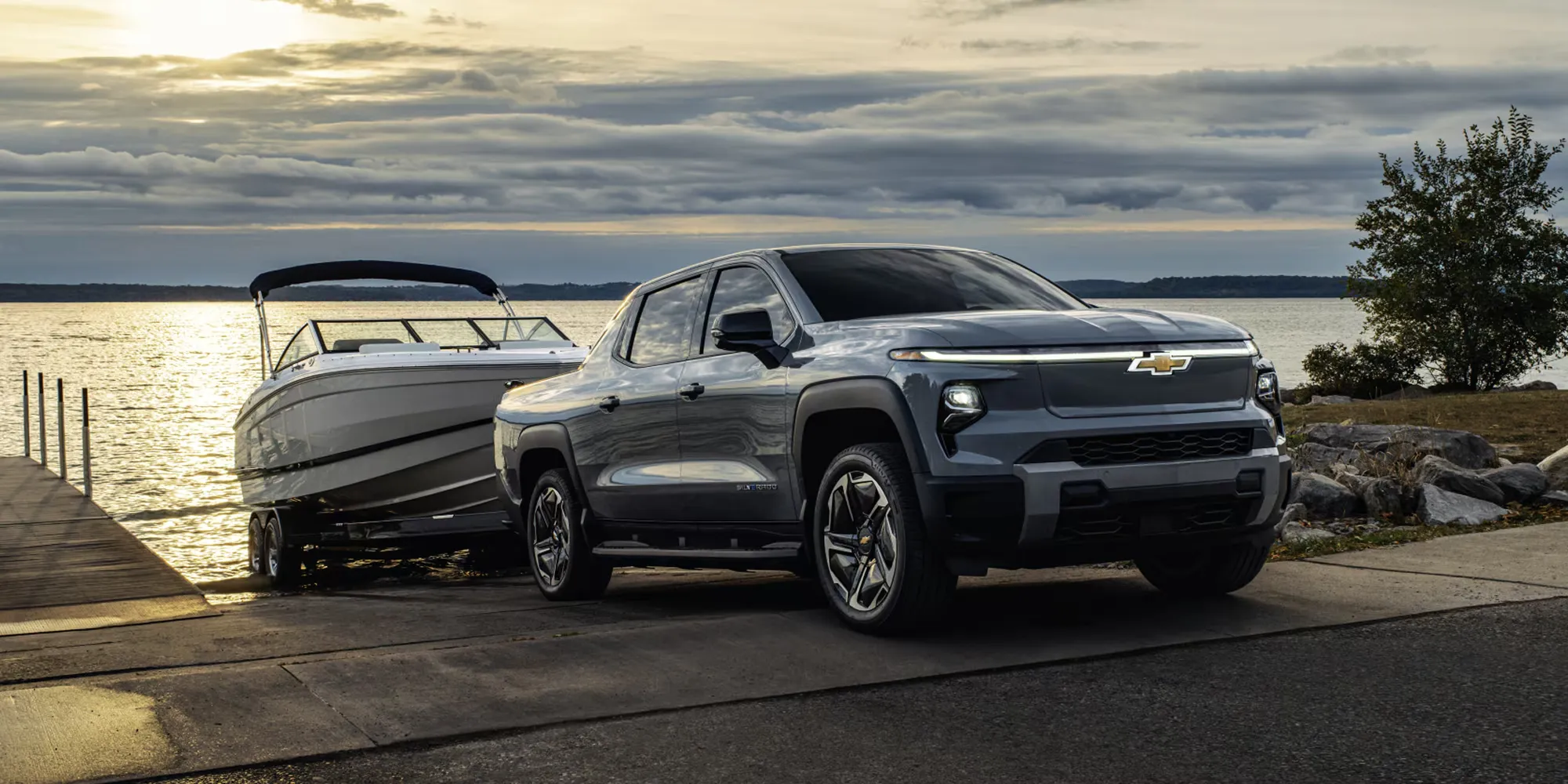 Chevrolet Silverado EV towing a boat by the water.