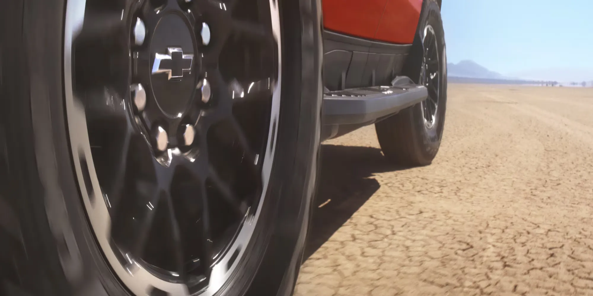 Close-up of a Chevrolet Silverado EV wheel on dry ground.