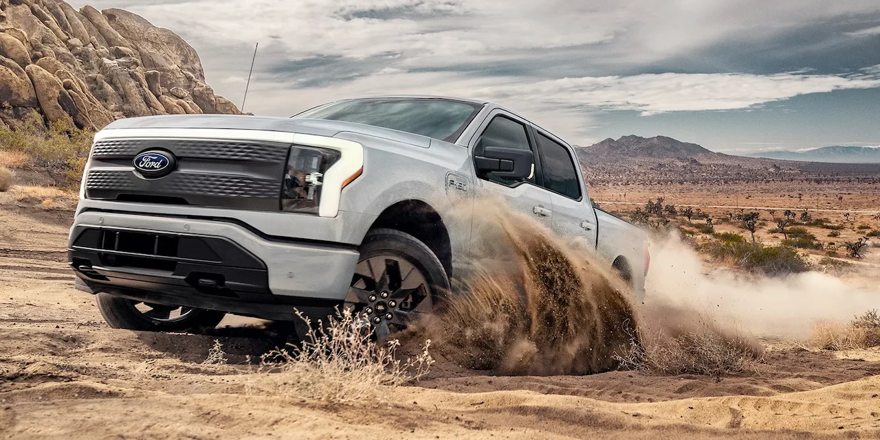 White 2026 Ford F-150 Lightning driving in the desert.