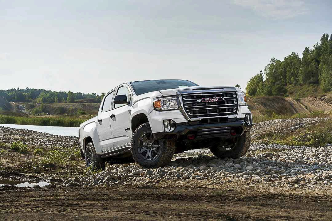 White GMC Canyon AT4 on rocky ground, illustrating engine and transmission checks.