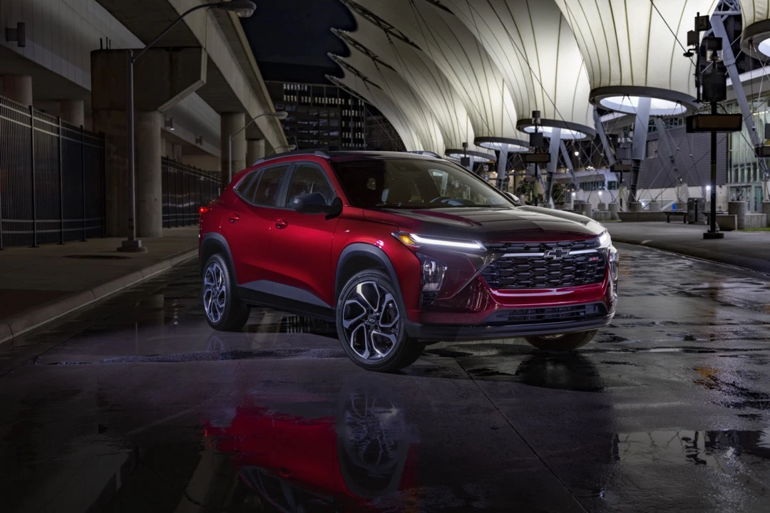 Chevrolet Trax RS 2024 rouge stationn&eacute; devant un b&acirc;timent color&eacute;.