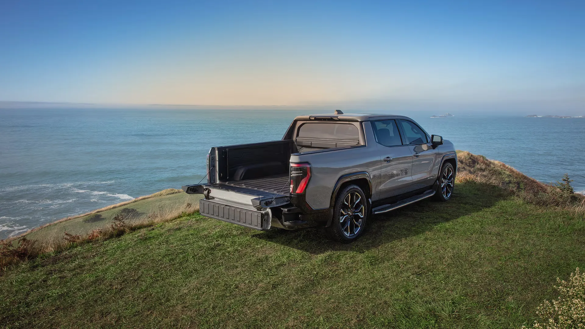 GMC Sierra EV 2026 stationn&eacute; en bord de mer, illustrant un pick-up &eacute;lectrique combinant autonomie, polyvalence et utilit&eacute;.