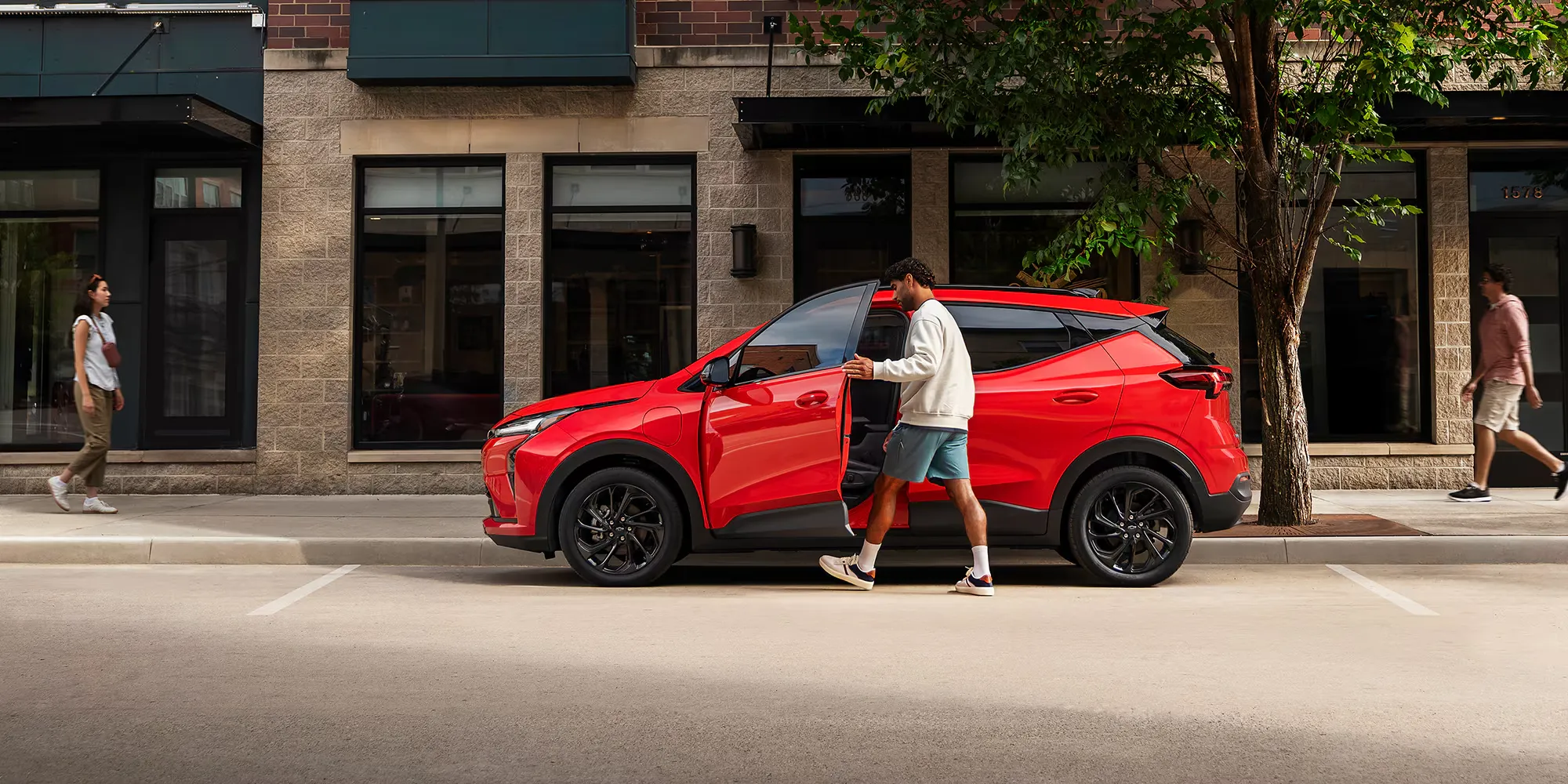Vue de profil du Chevrolet Bolt 2027 rouge stationné en ville.