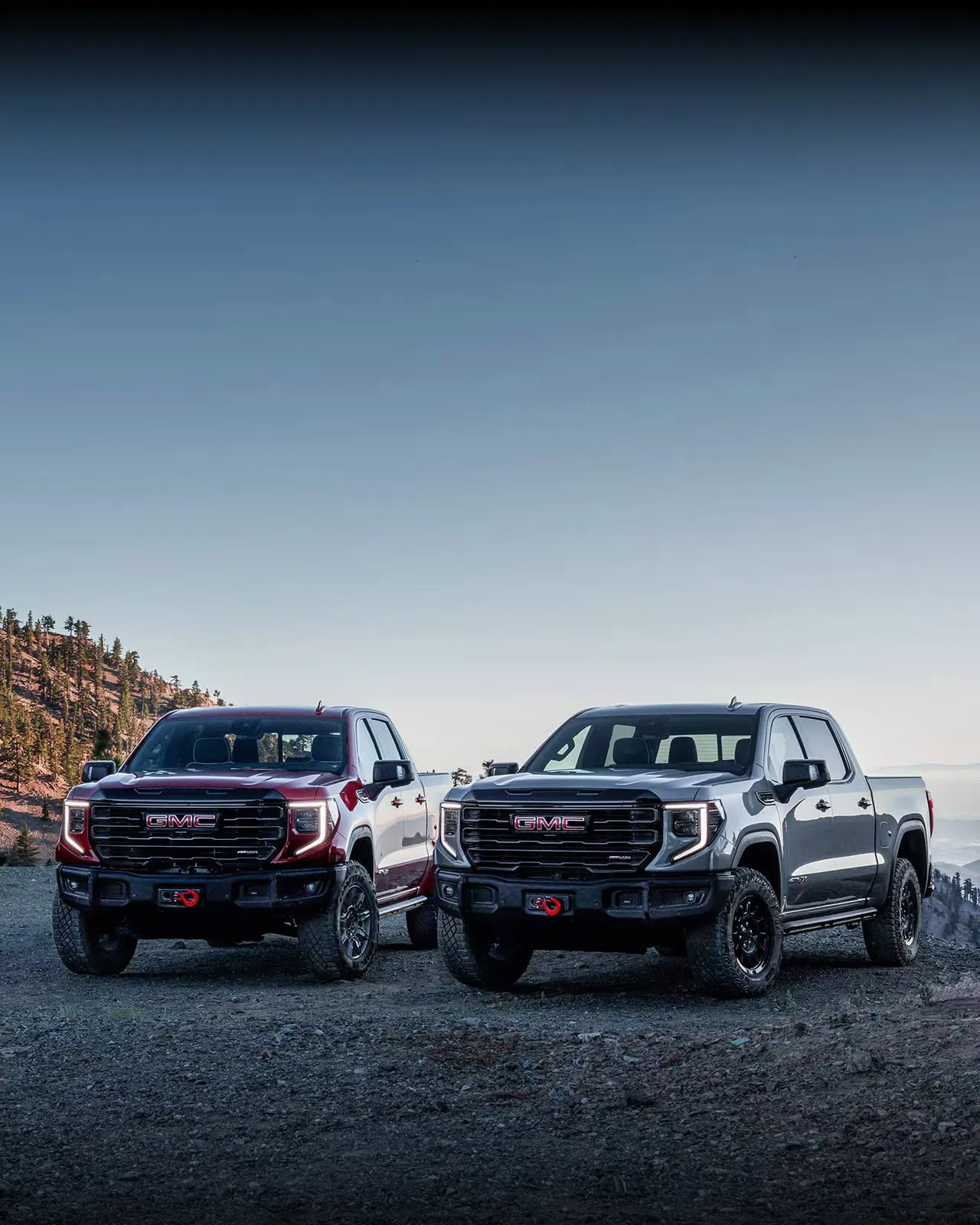 Deux versions du GMC Sierra 1500 2027 sur un terrain montagneux.