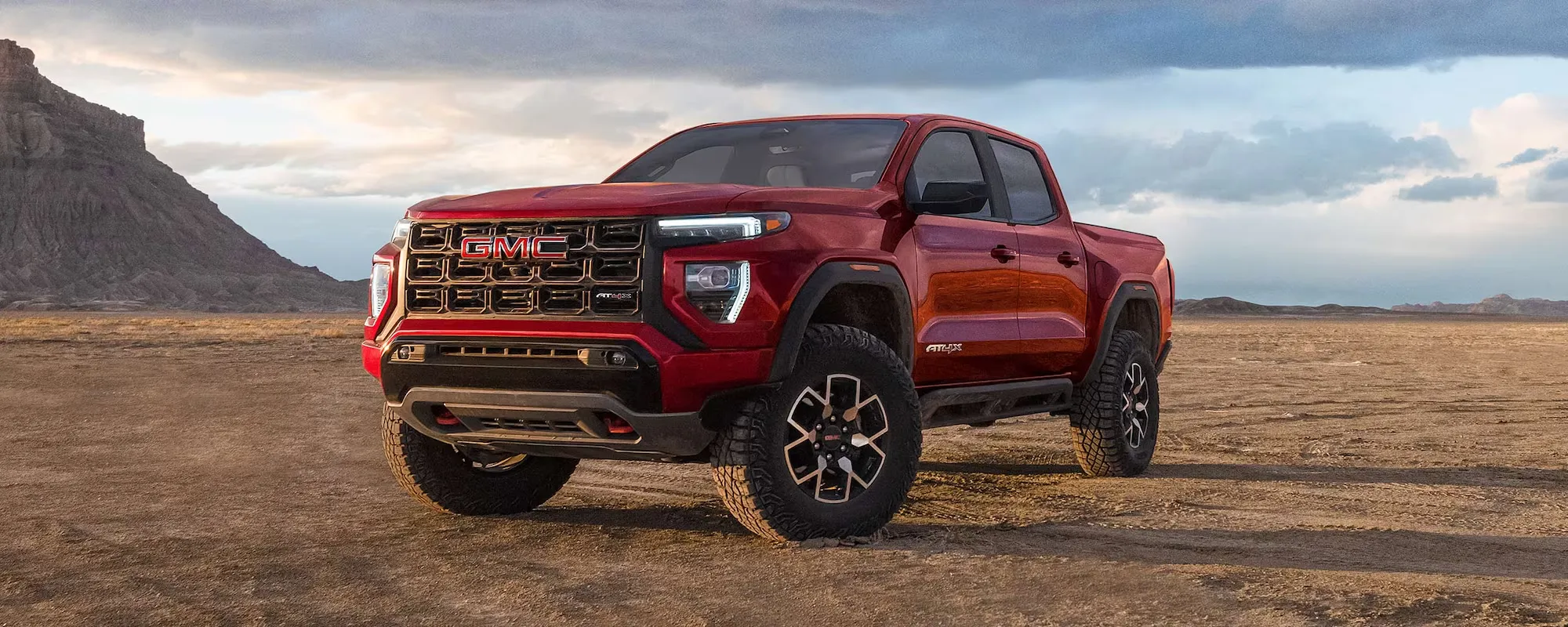 GMC Canyon AT4X rouge sur un terrain désertique.
