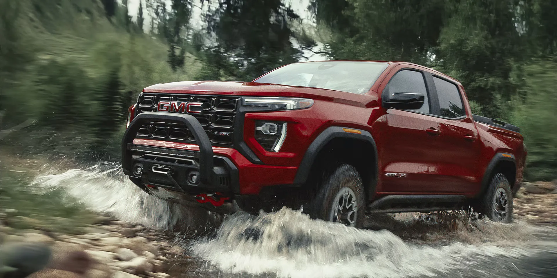GMC Canyon AT4X 2026 rouge traversant un cours d&rsquo;eau.