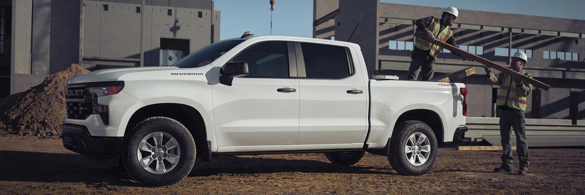 Chevrolet Silverado blanc auprès de travailleurs sur un chantier de construction.