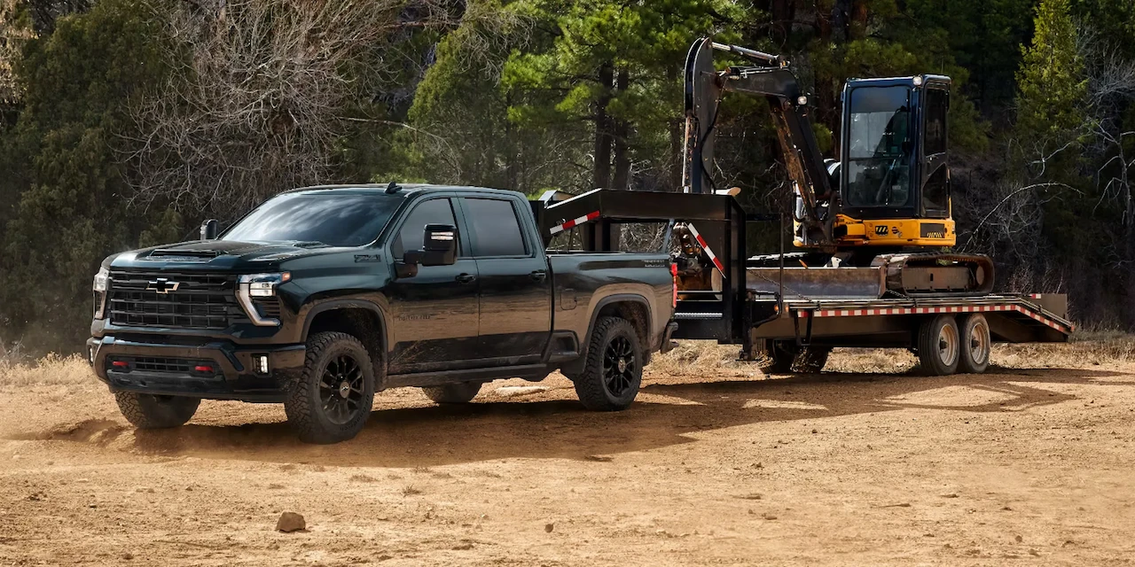 Chevrolet Silverado 2500 HD remorquant une excavatrice sur un chantier.