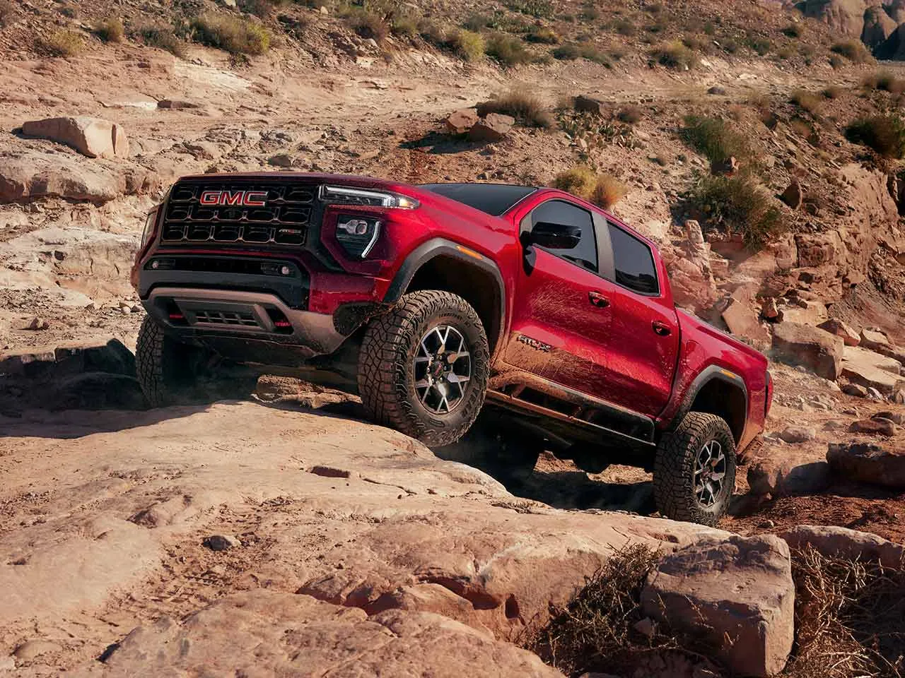 GMC Canyon rouge en conduite hors route sur un terrain rocheux.