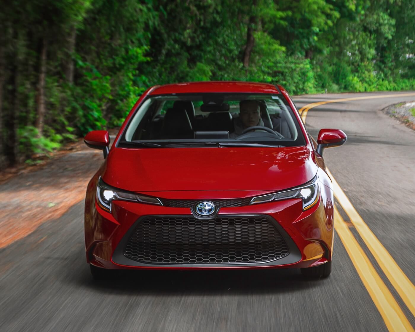 front view of red 2022 Toyota Corolla Hybrid driving on a road
