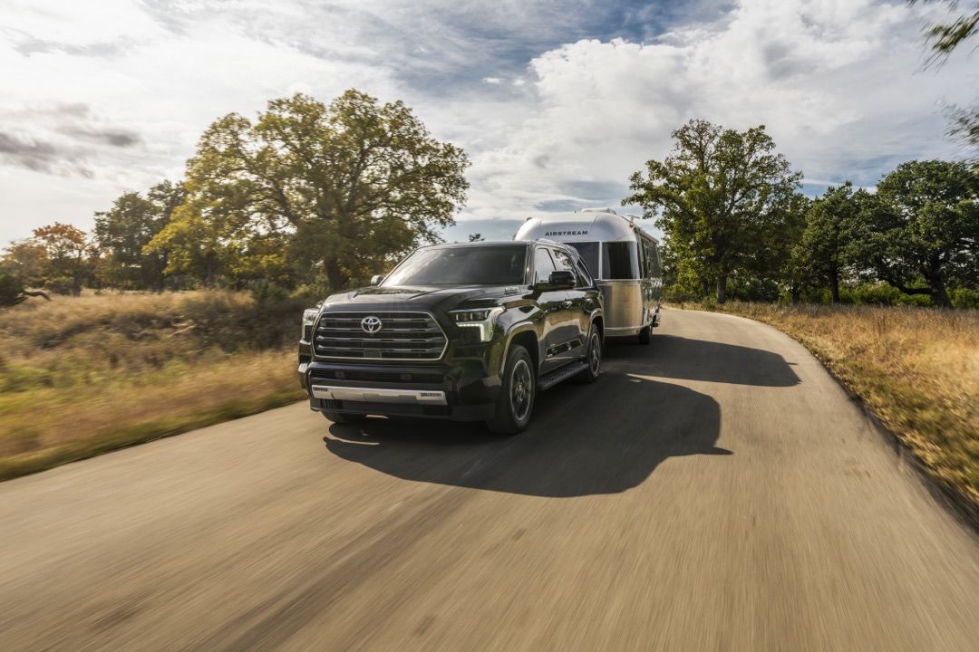 The 2023 Toyota Sequoia Limited towing a travel trailer on a country road