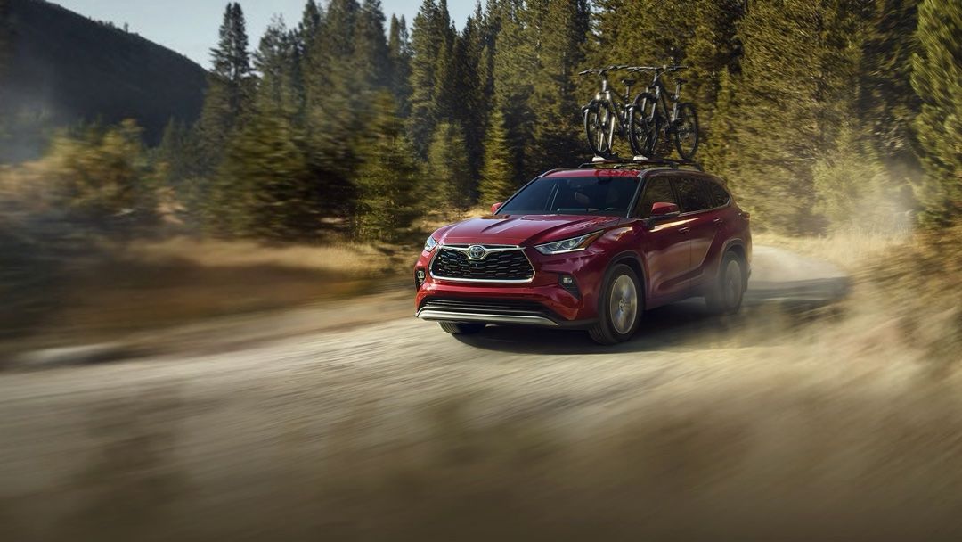 Le Toyota Highlander 2024 qui roule sur un chemin de terre avec 2 vélo sur le toit.