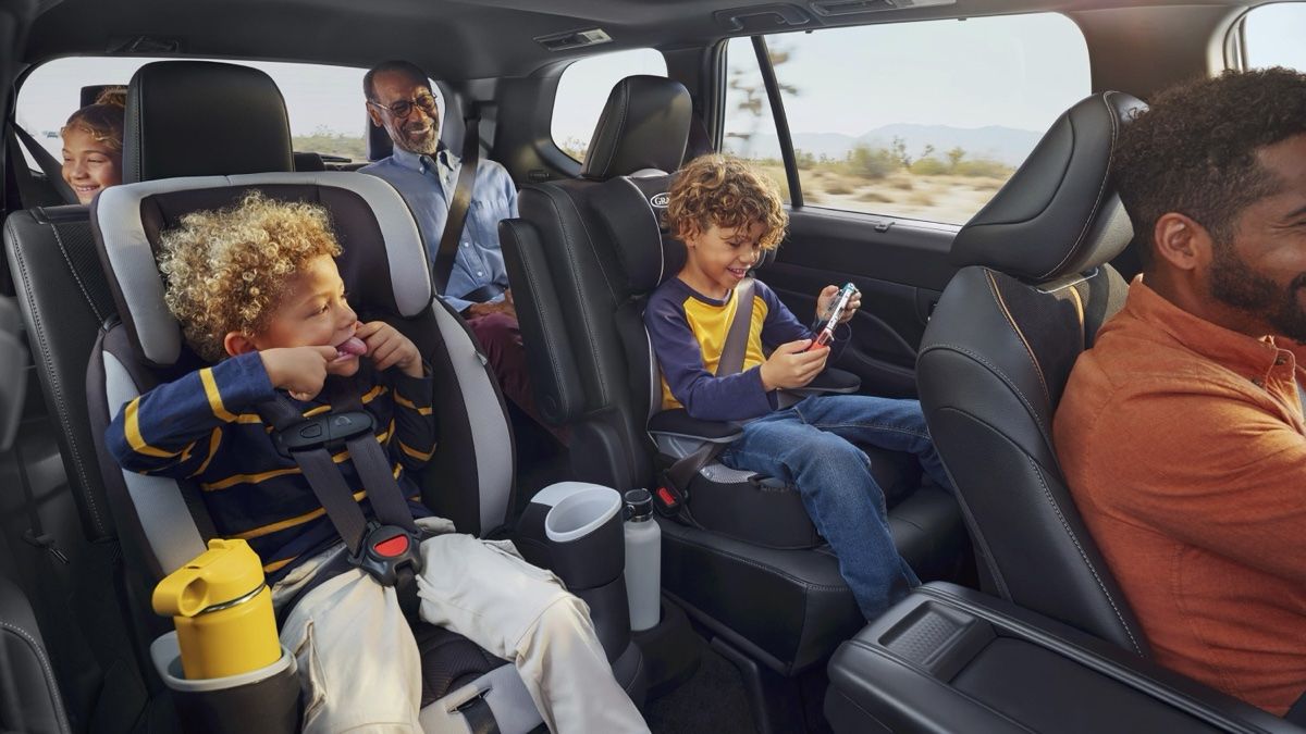 Une grande famille heureuse de prendre la route de le Toyota Grand Highlander.