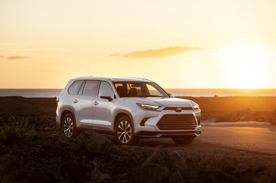 Front 3/4 view of 2024 Toyota Grand Highlander SUV parked outdoors at dusk.