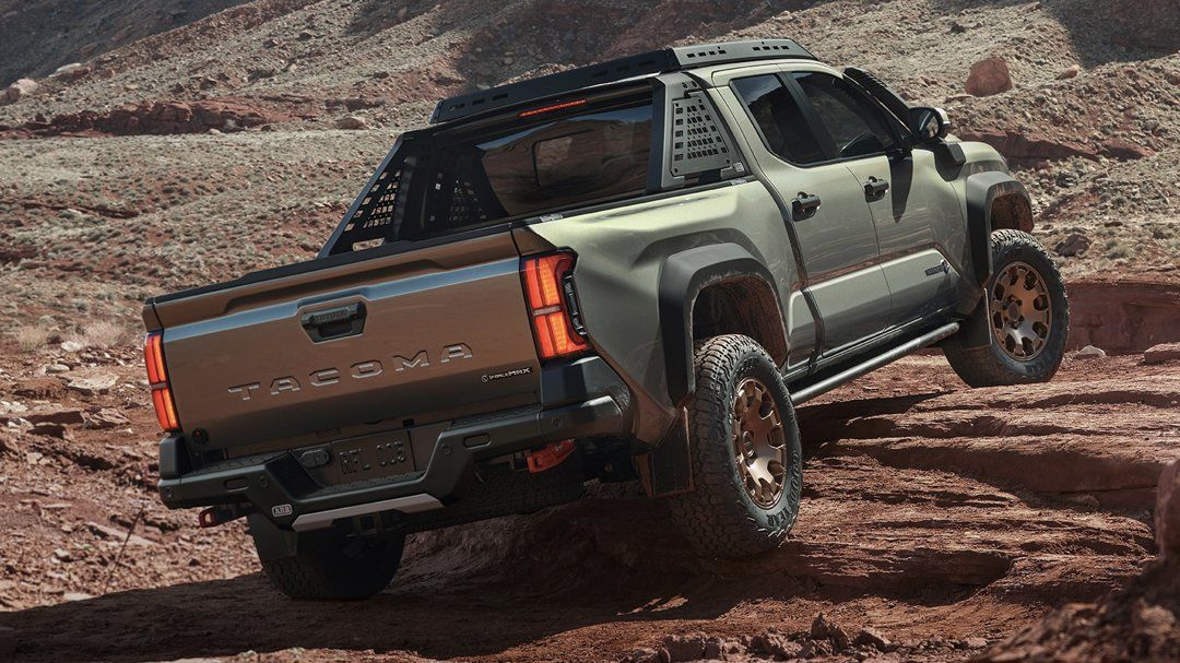 Rear view of Toyota Tacoma rolling over rocks.