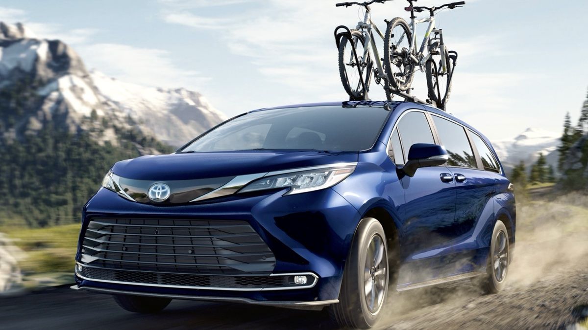 The Toyota Sienna 2024 on a gravel road with 2 bikes on the roof.