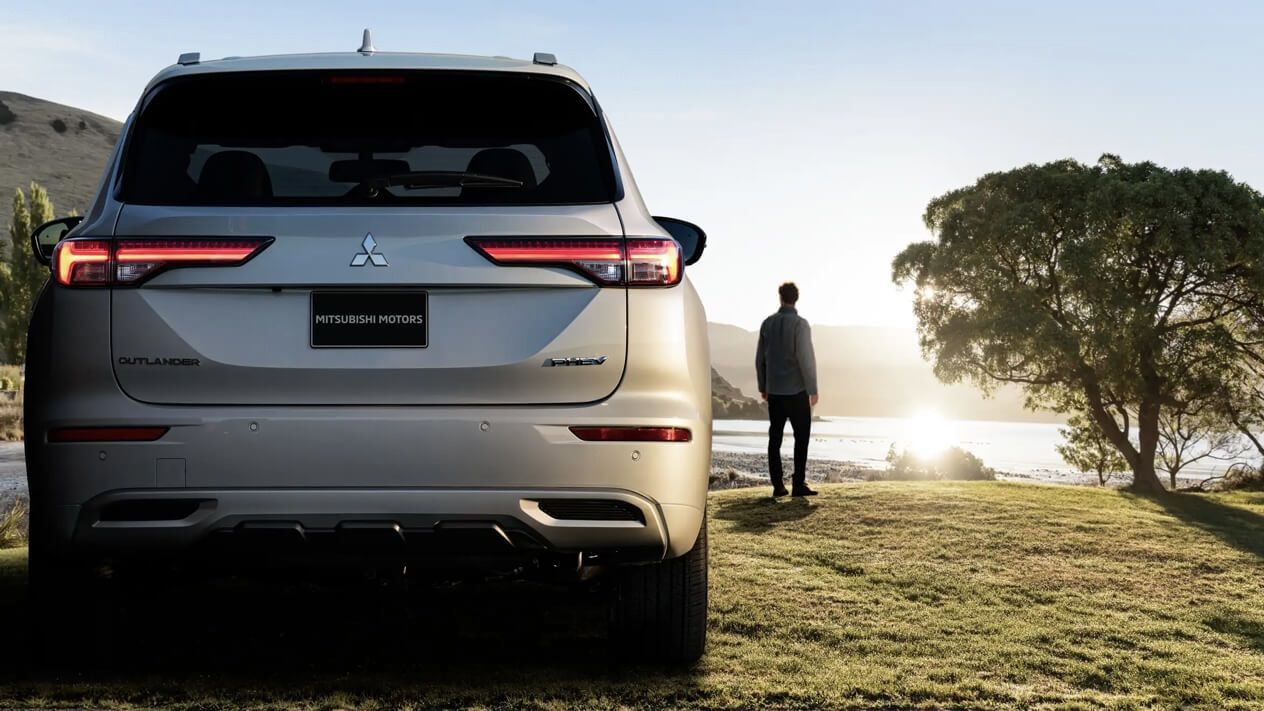 The Mitsubishi Outlander parked by the water at sunrise.