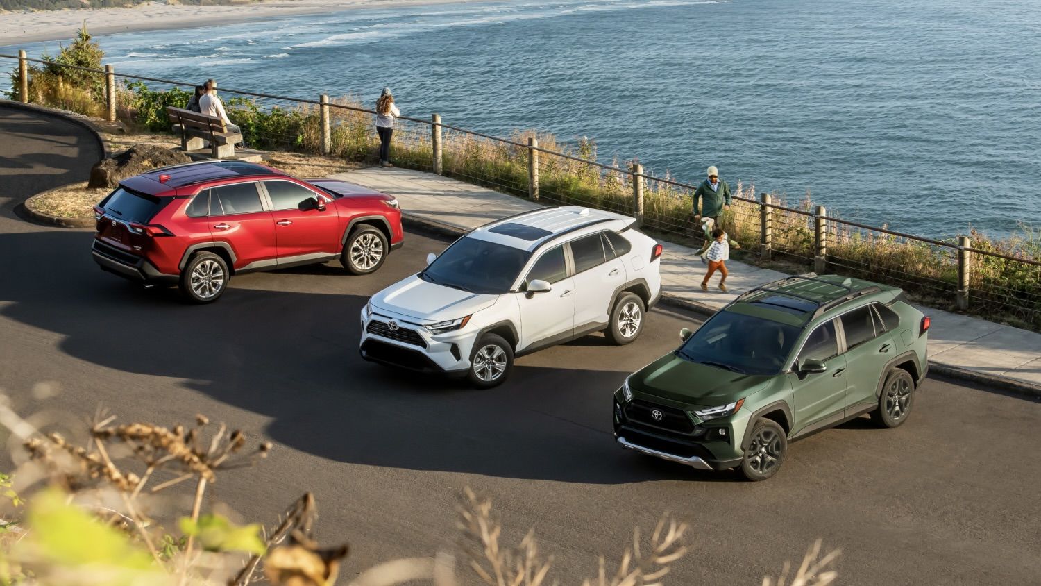 Different versions of the Toyota RAV4 parked by the water.