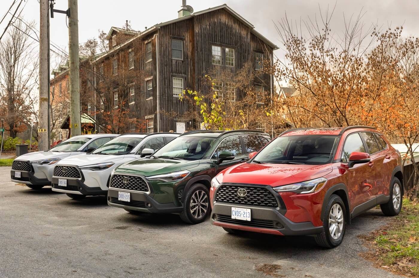 Four 2022 Toyota Corolla Cross SUVs in different colors parked in the yard of a large barn