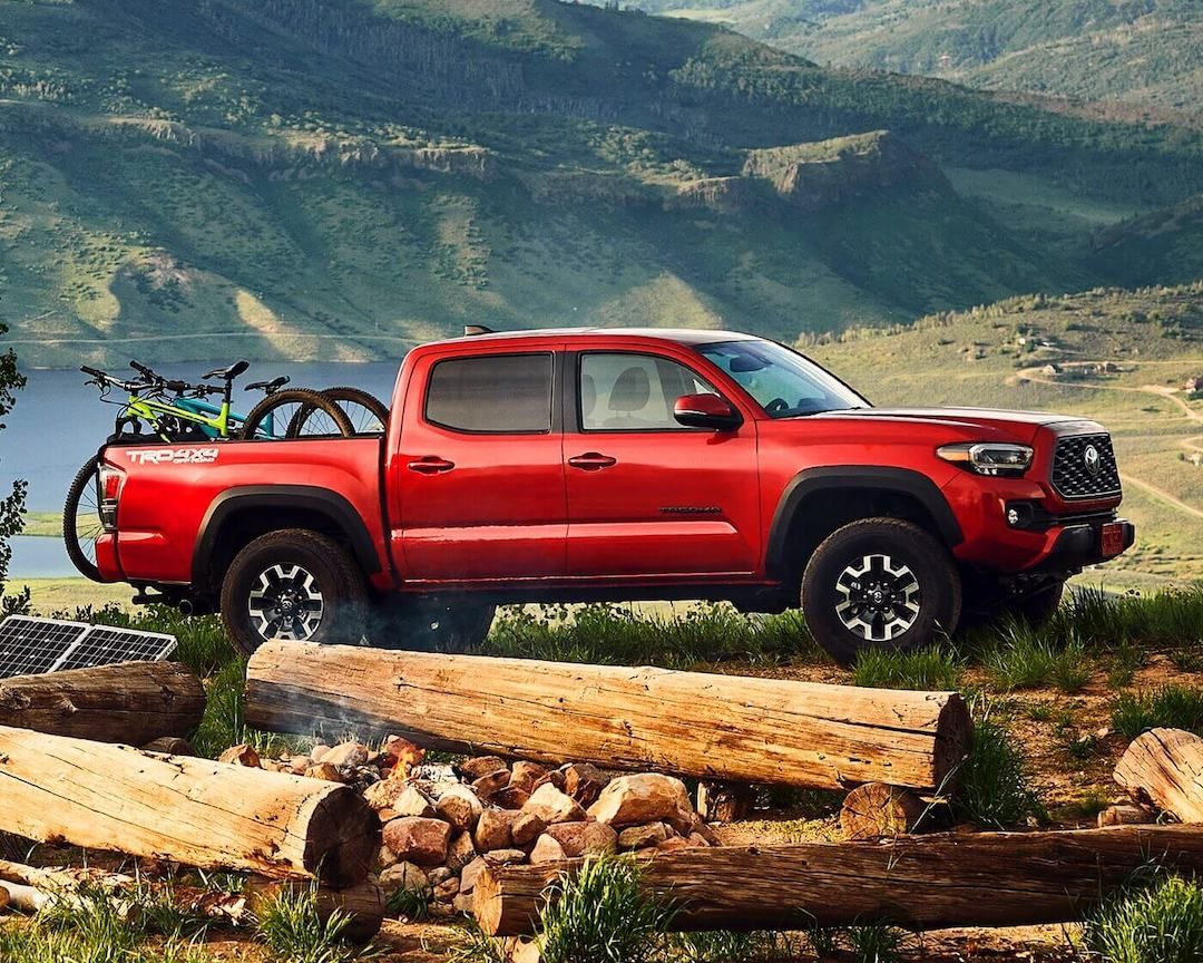 Side view of a barcelona red 2022 Toyota Tacoma TRD Sport parked next to a campfire