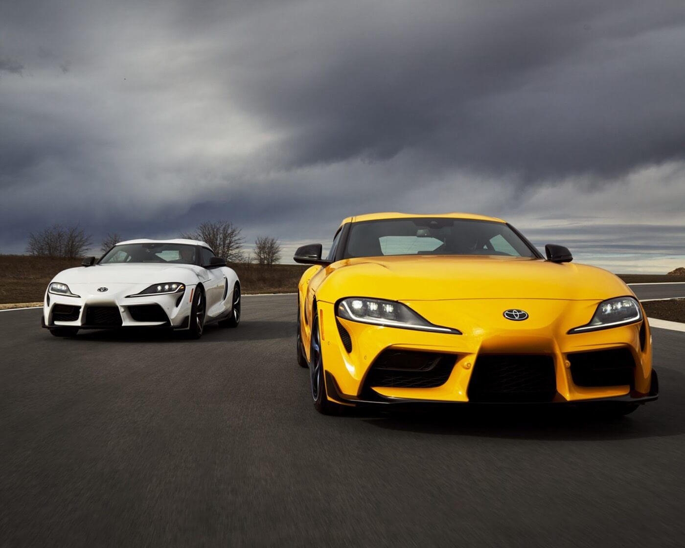 Front view of two 2022 Toyota GR Supra racing an outdoor race track