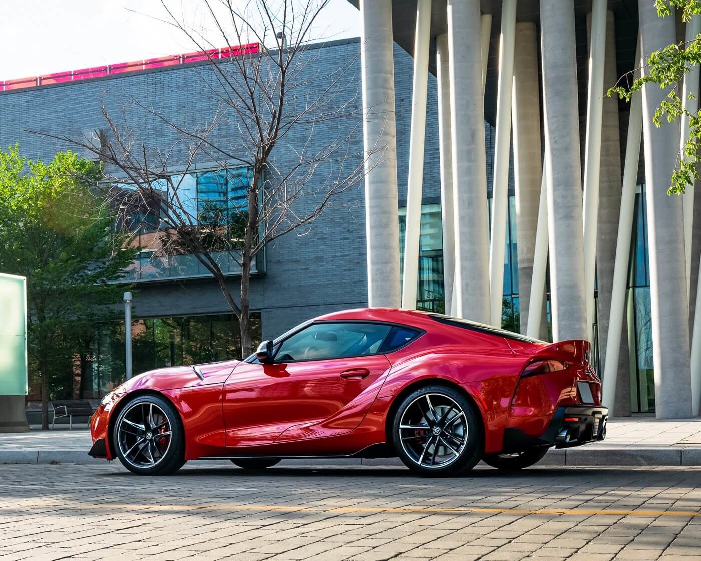 Side and 1/4 rear view of a 2022 Toyota GR Supra 3.0 Renaissance Red 2.0 parked on a cobblestone