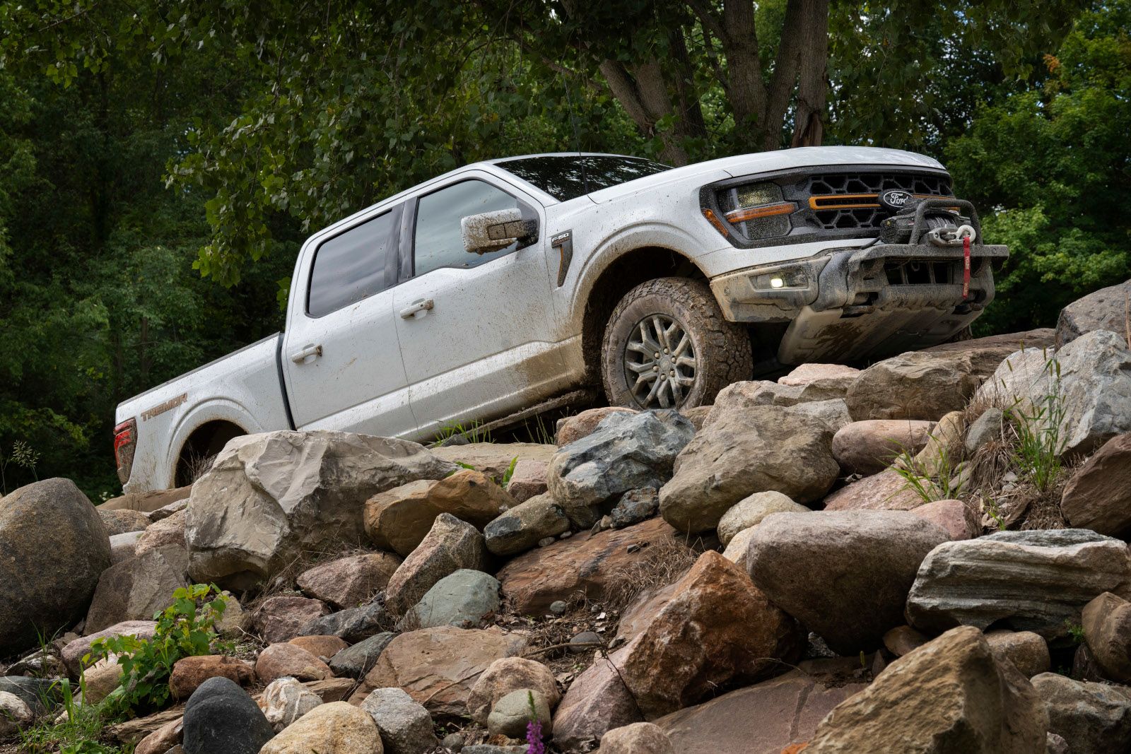 2025 Ford F-150 - a white 2025 Ford F-150 climbing a pile of rocks - Humberview Group in Ontario
