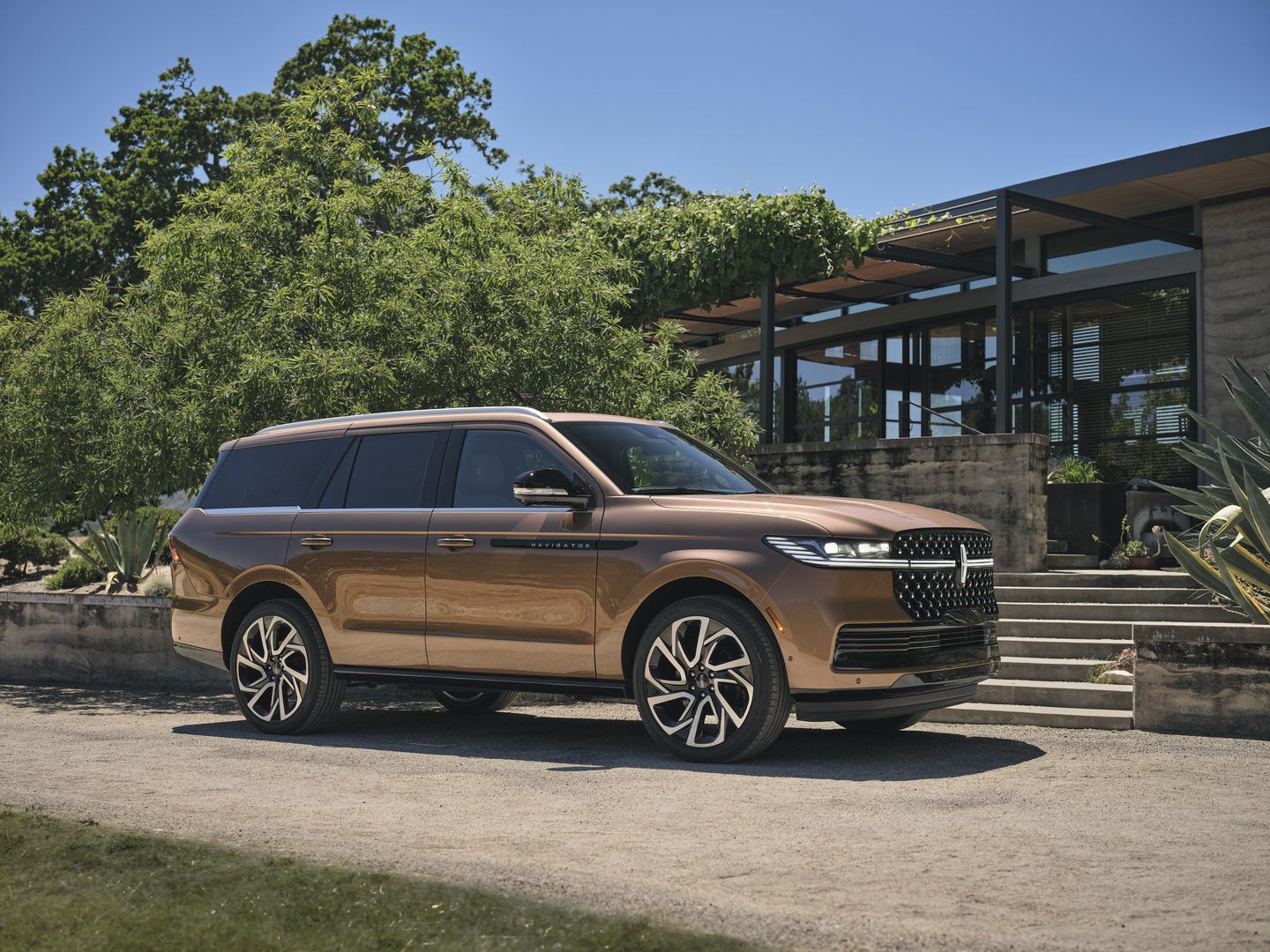 2025 Lincoln Navigator - a copper 2025 Lincoln Navigator parked on a driveway in front of a modern home - Mayfield Lincoln - Lincoln car dealership in Brampton, Ontario