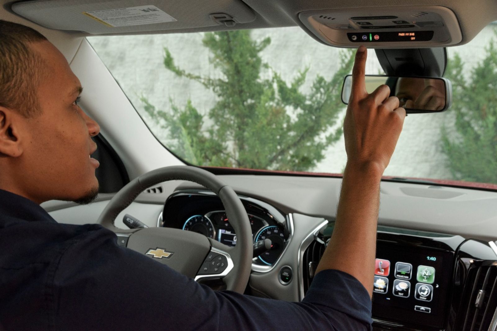 Chevrolet Traverse - interior view of a driver pressing the OnStar button located on the rearview mirror - Humberview Chevrolet Buick GMC - Chevrolet car dealership in Toronto, Ontario