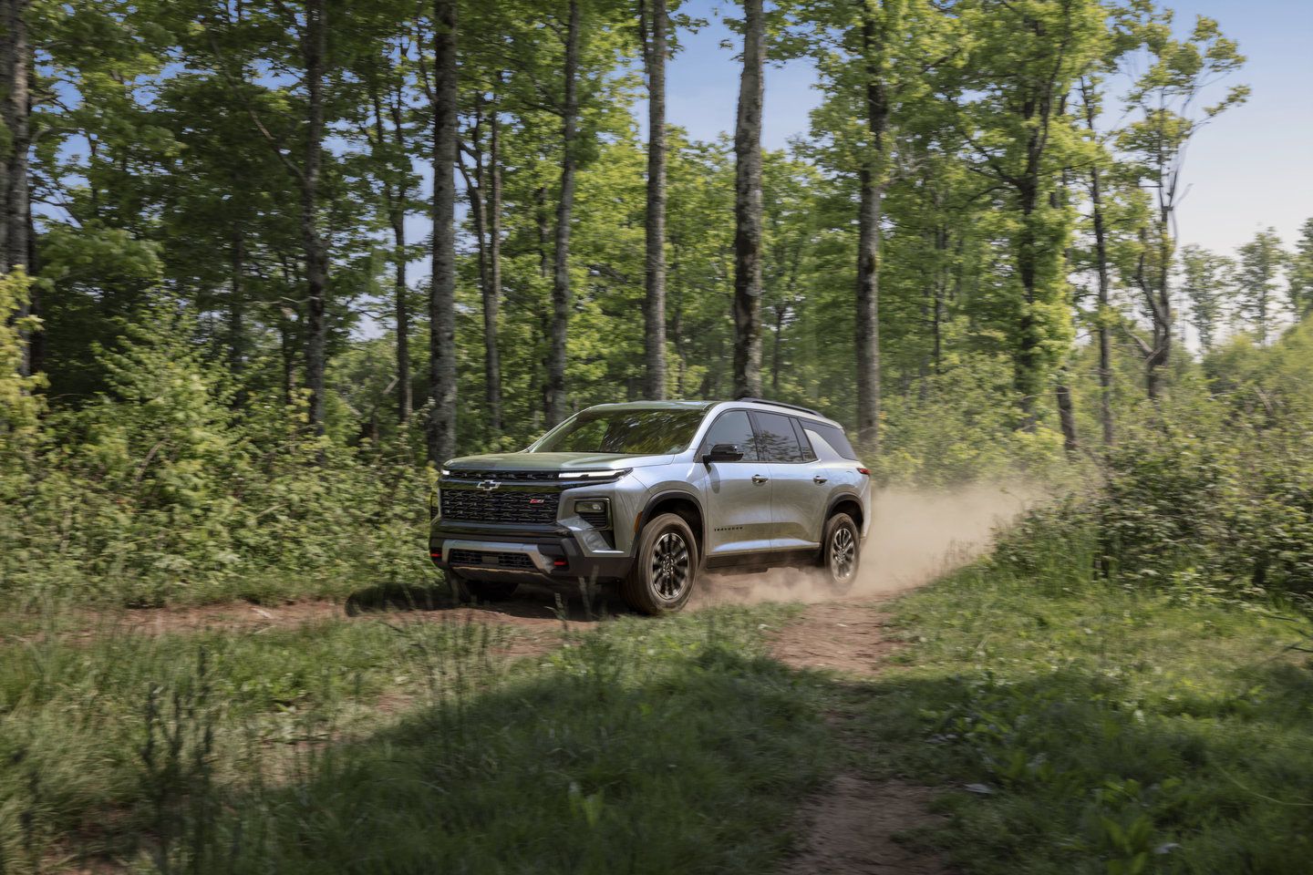 2025 Chevrolet Traverse a silver 2025 Chevrolet Traverse Z71 driving on a dirt trail through a forest - City Chevrolet Buick GMC - new car dealerships in Ontario