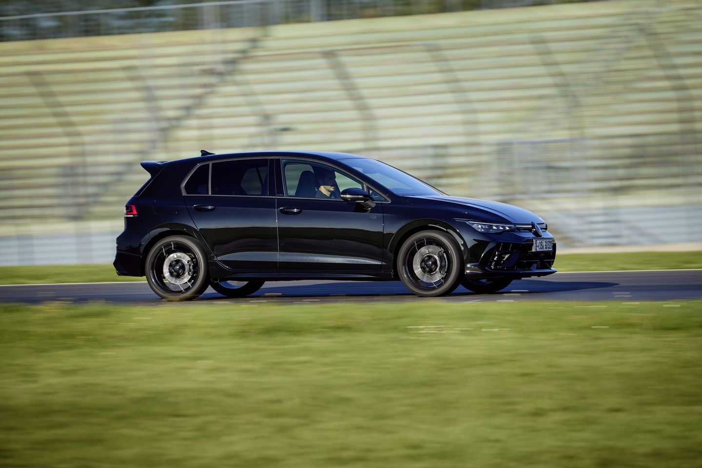 2025 Volkswagen Golf R side profile of a black Golf R driving on a racetrack - Humberview Volkswagen - new car dealerships in Ontario