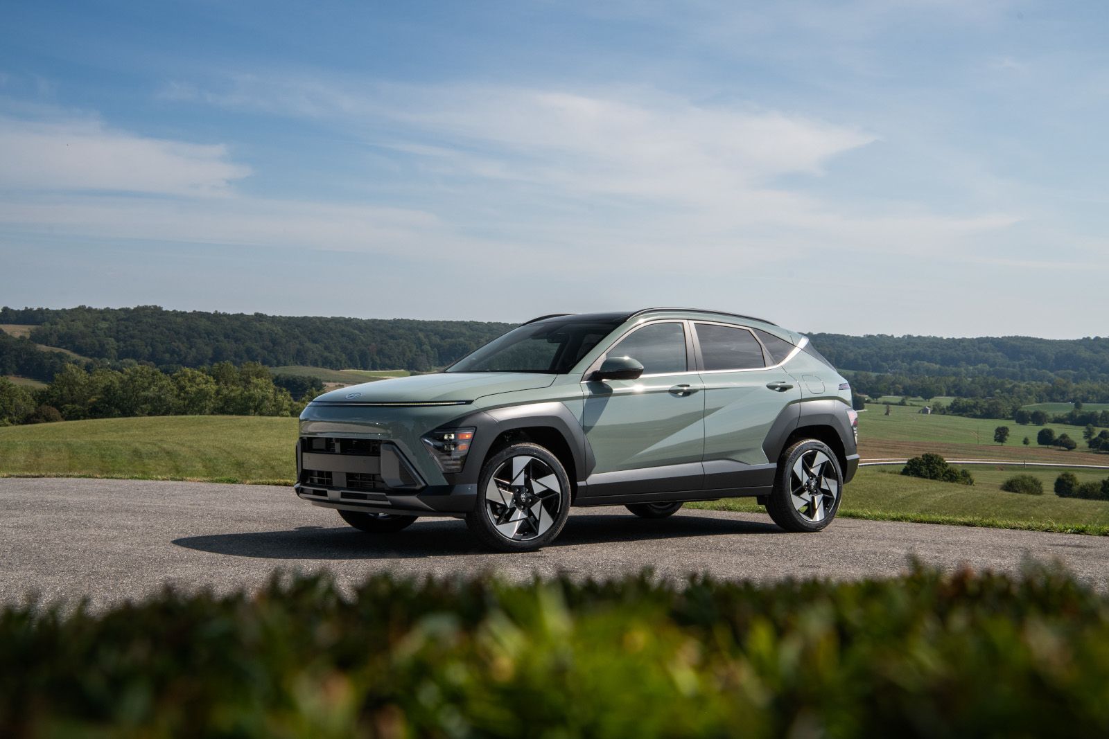 2025 Hyundai Kona - a light green 2025 Hyundai Kona parked on a road with rolling hills in the background - Humberview Group - new car dealerships in Ontario